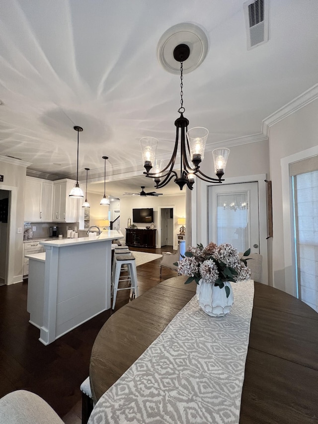 dining area with ornamental molding, dark wood-style flooring, visible vents, and an inviting chandelier