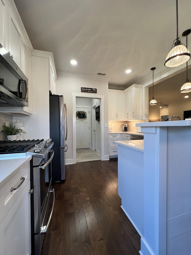 kitchen featuring pendant lighting, stainless steel appliances, light countertops, dark wood-type flooring, and white cabinets