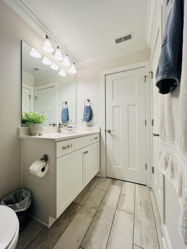 bathroom with wood finish floors, visible vents, crown molding, and vanity