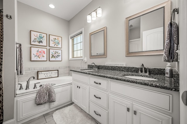 bathroom with double vanity, a garden tub, and a sink