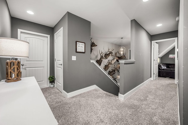 hallway featuring carpet, recessed lighting, baseboards, and an inviting chandelier