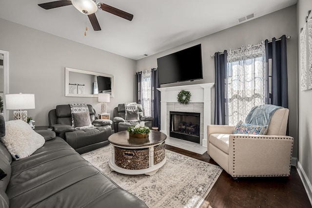 living area featuring visible vents, dark wood finished floors, a wealth of natural light, and a tile fireplace