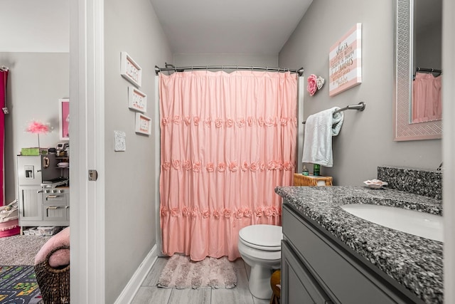 bathroom with toilet, baseboards, vanity, and a shower with curtain