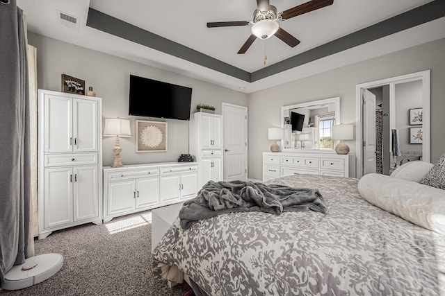 bedroom with light carpet, a tray ceiling, and visible vents