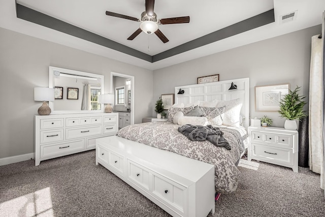 bedroom with baseboards, visible vents, a tray ceiling, and dark carpet