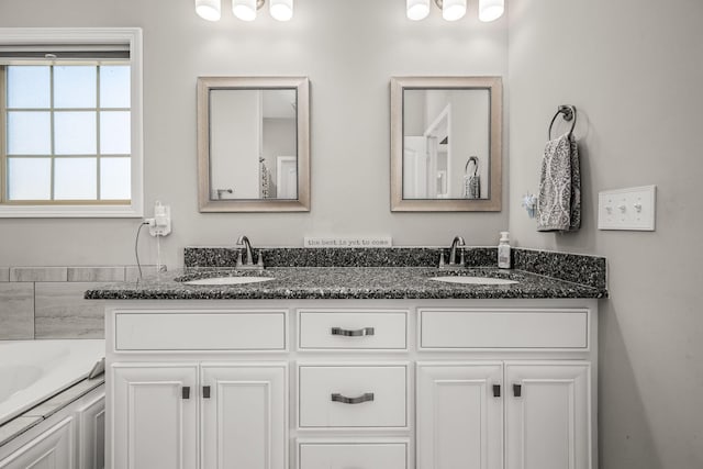 bathroom featuring double vanity, a washtub, and a sink