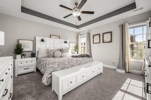 bedroom featuring baseboards, visible vents, a raised ceiling, a ceiling fan, and dark colored carpet