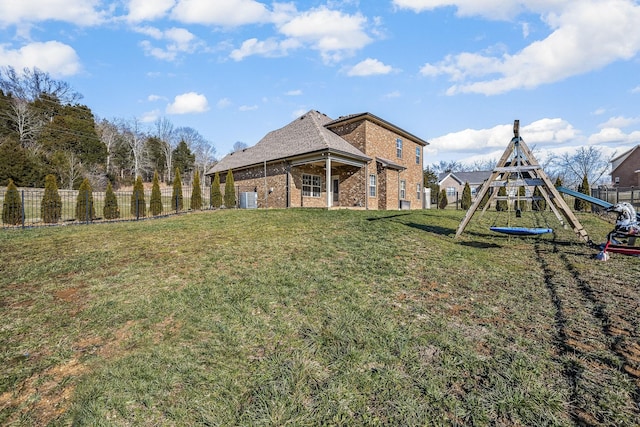 rear view of property with a playground, central air condition unit, brick siding, fence, and a lawn