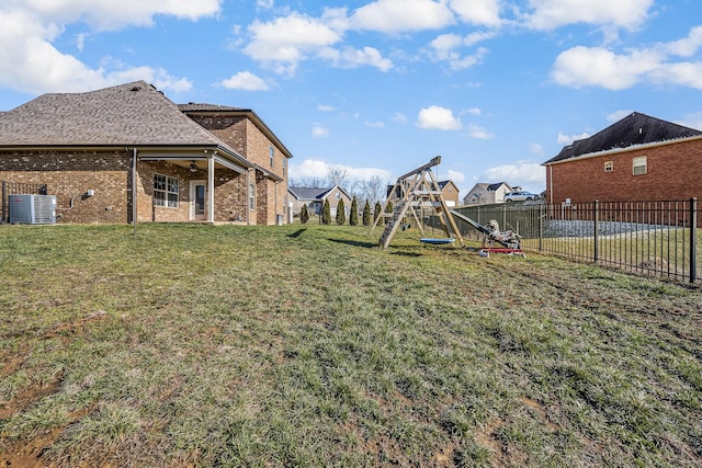 view of yard with central AC, a playground, and a fenced backyard