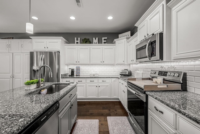 kitchen featuring stainless steel appliances, visible vents, white cabinetry, a sink, and dark stone countertops