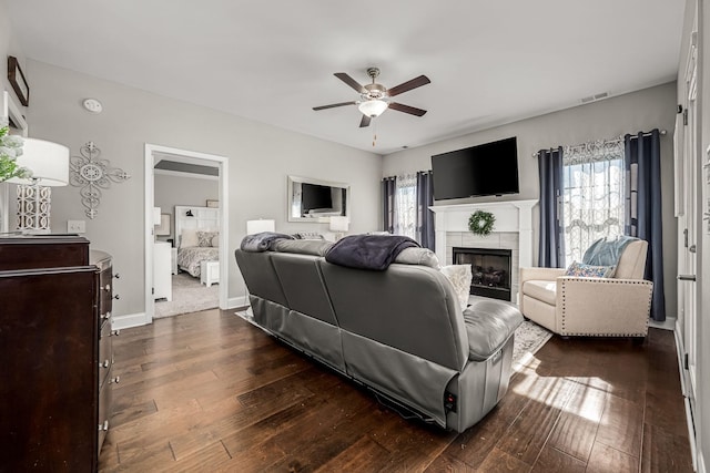 living area featuring dark wood-style floors, a fireplace, visible vents, and a ceiling fan