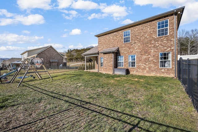 rear view of property with a fenced backyard, a lawn, a playground, and brick siding