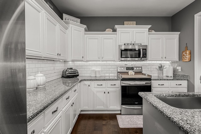 kitchen with light stone countertops, white cabinetry, stainless steel appliances, and a sink