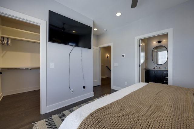 bedroom with recessed lighting, a sink, dark wood finished floors, baseboards, and a walk in closet