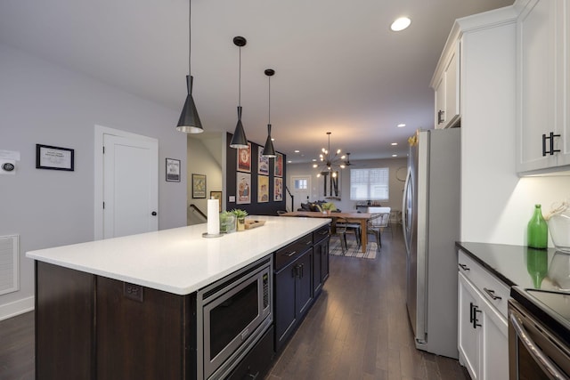 kitchen featuring dark brown cabinetry, white cabinets, a center island, stainless steel appliances, and pendant lighting