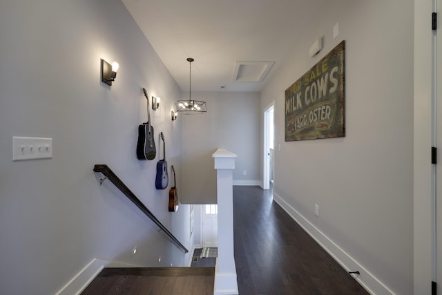 hallway with dark wood-style floors, baseboards, and an upstairs landing