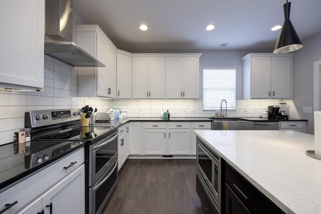 kitchen with white cabinetry, wall chimney exhaust hood, appliances with stainless steel finishes, and decorative light fixtures