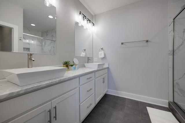 full bath with double vanity, a sink, a marble finish shower, and baseboards