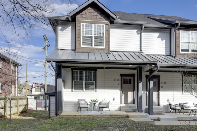 multi unit property featuring covered porch, metal roof, a standing seam roof, and fence