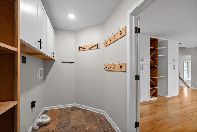 clothes washing area featuring cabinet space, hookup for a washing machine, baseboards, and wood finished floors