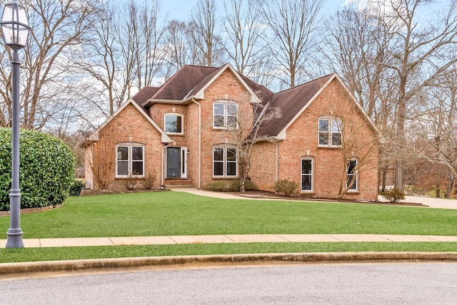 traditional-style home featuring brick siding, roof with shingles, and a front yard