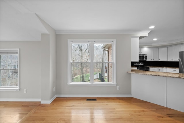 kitchen with visible vents, light stone countertops, stainless steel appliances, light wood-type flooring, and white cabinetry