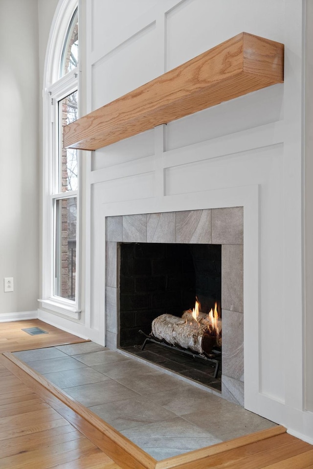 room details with visible vents, wood finished floors, and a tile fireplace