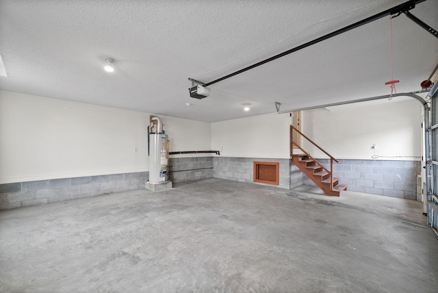 garage featuring concrete block wall, water heater, and a garage door opener