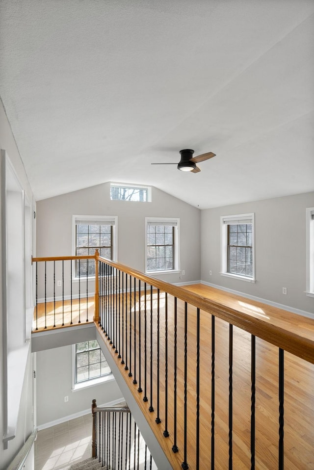 stairway featuring a ceiling fan, lofted ceiling, baseboards, and wood finished floors