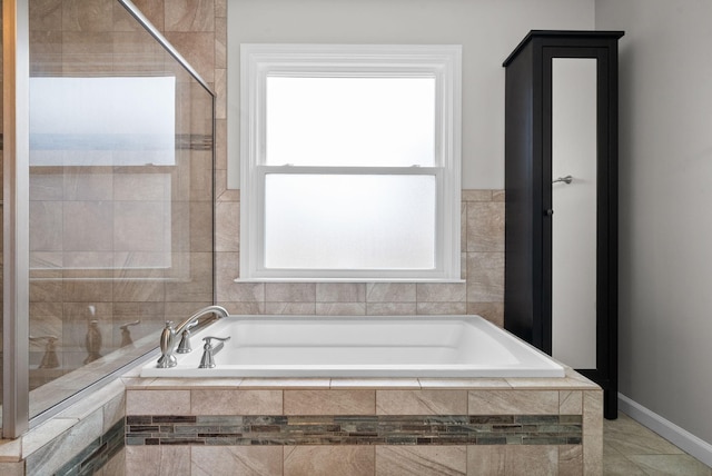 full bathroom with baseboards, a bath, and tiled shower