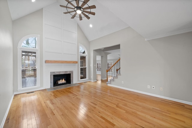 unfurnished living room with baseboards, stairway, a fireplace, and light wood-style floors