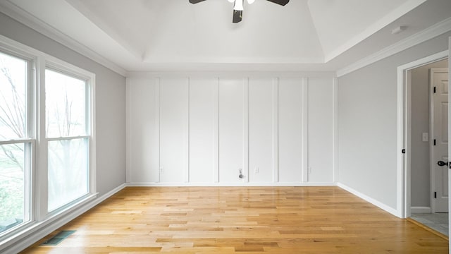 spare room with light wood finished floors, plenty of natural light, visible vents, and a raised ceiling