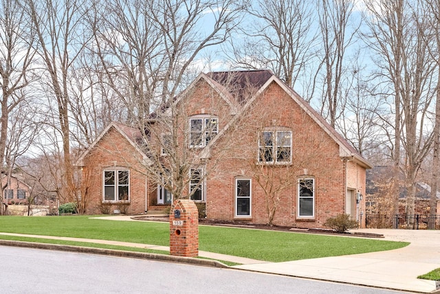 traditional-style home featuring driveway, brick siding, and a front yard