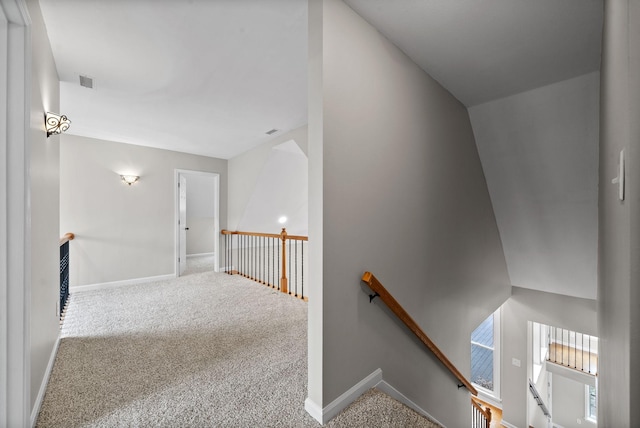 hall with visible vents, baseboards, carpet flooring, and an upstairs landing