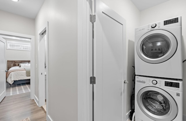 laundry room featuring laundry area, light wood-type flooring, and stacked washing maching and dryer