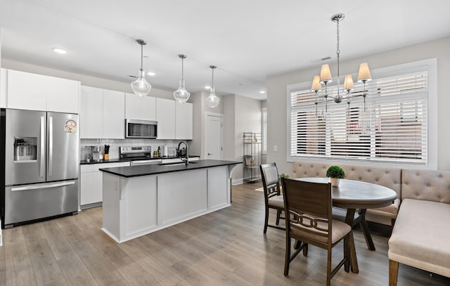 kitchen featuring dark countertops, white cabinetry, stainless steel appliances, and hanging light fixtures