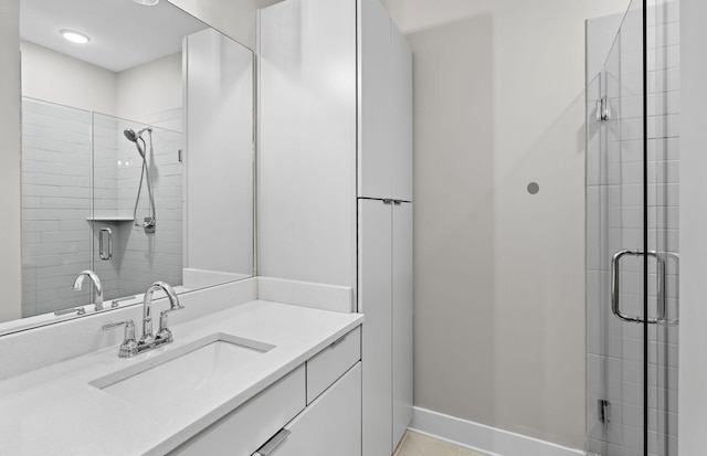 bathroom with a stall shower, baseboards, and vanity