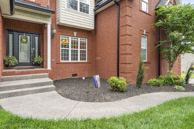 view of exterior entry featuring crawl space and brick siding