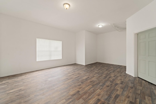 empty room featuring dark wood-type flooring and baseboards