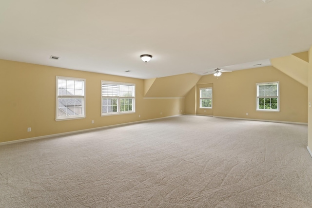 bonus room featuring light colored carpet, visible vents, vaulted ceiling, and baseboards