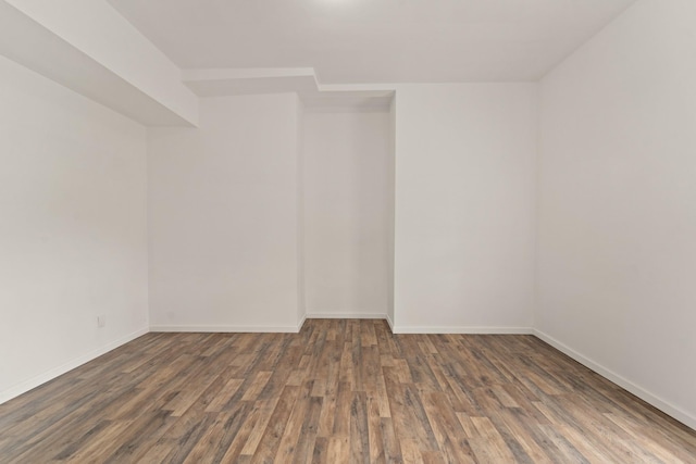 empty room with dark wood-type flooring and baseboards