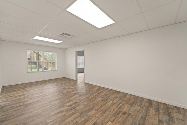 empty room with dark wood-style floors, a paneled ceiling, visible vents, and baseboards