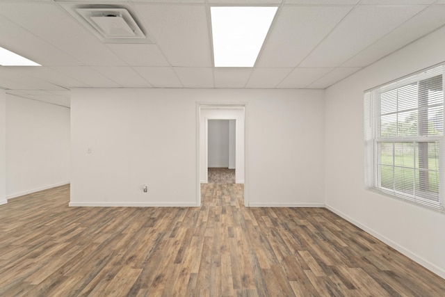 basement featuring a drop ceiling, dark wood finished floors, visible vents, and baseboards