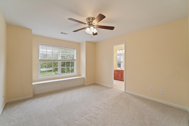 spare room with light carpet, visible vents, baseboards, and a ceiling fan