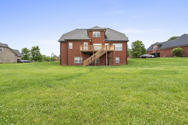 rear view of house with a deck, brick siding, a yard, and stairway