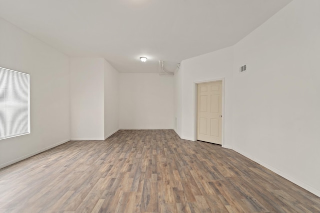 unfurnished room with wood finished floors, visible vents, and baseboards