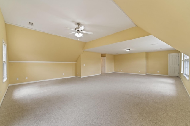 additional living space with lofted ceiling, carpet flooring, a ceiling fan, visible vents, and baseboards