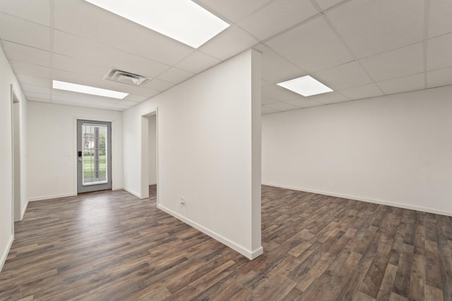 empty room with a paneled ceiling, dark wood-style flooring, and visible vents