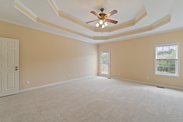 spare room with a raised ceiling, ornamental molding, light carpet, ceiling fan, and baseboards