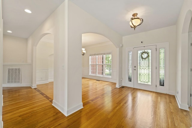 foyer entrance featuring light wood finished floors, recessed lighting, visible vents, a decorative wall, and wainscoting